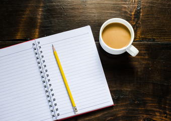 notebook pen and cup of coffee in wood table