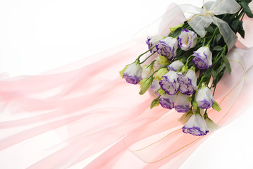 Bouquet of eustoma flowers tied with white ribbon on pink cloth