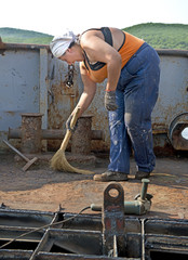 Woman painter removes old paint on a fishing seiner