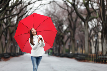 Woman with red umbrella walking in park in fall