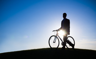 Silhouette of Businessman Holding Bicycle