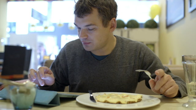 Man using pad and having dinner in cafe
