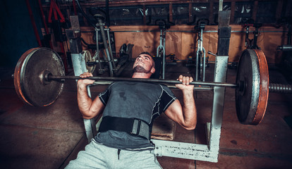 Young man lifting the barbell in the gym. - obrazy, fototapety, plakaty