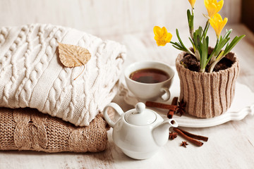 Cup of hot drink, knitting clothes, cinnamon and flowers. winter
