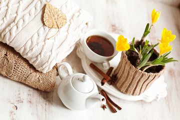 Cup of hot drink, knitting clothes, cinnamon and flowers. winter