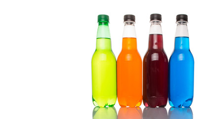 Multicolored soda drinks in bottles over white background