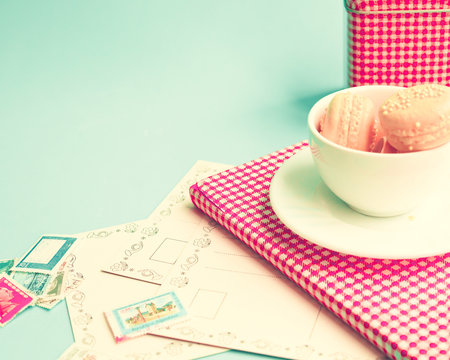 Pink macaroons in a tea cup over book