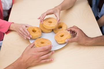 Obraz na płótnie Canvas Business team reaching for doughnuts on table
