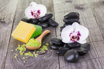Orchids, soaps, bath salt and black stones on weathered deck