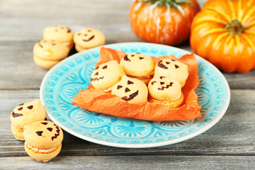 Tasty Halloween macaroons on plate, on wooden table