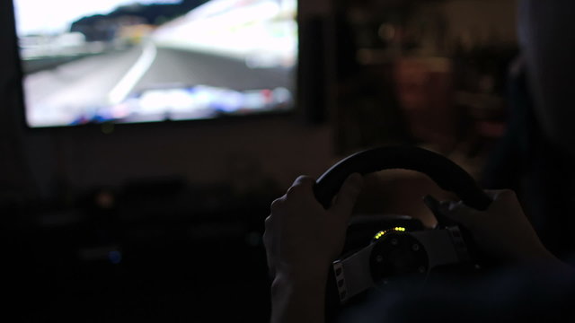 Playing racing game with steering wheel simulator