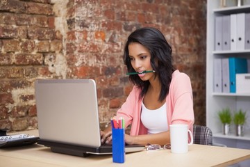 Woman siiting and holding a pencil in her mouth