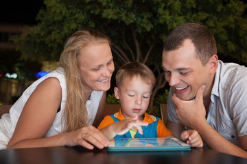 Family of three with pad in outdoor cafe