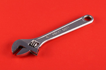 CAdjustable wrench or spanner on a red background.