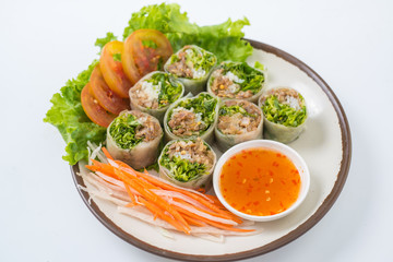 Fresh spring rolls with dipping sauce on a white background.