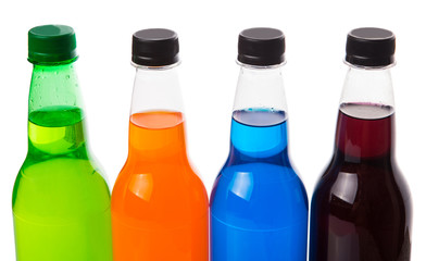 Multicolored soda drinks in bottles over white background
