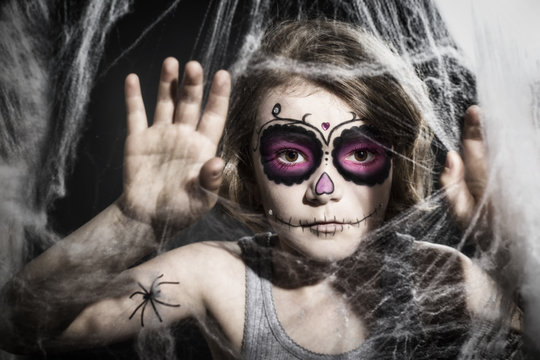 kleines Mädchen mit Sugar Skull Make up, hinter Spinnweben