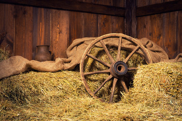Interior of a rural farm - hay, wheel, pitcher. © Yarkovoy