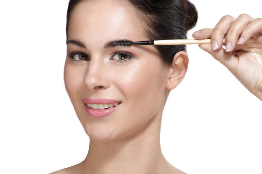 Beautiful young woman applying eyebrow brush