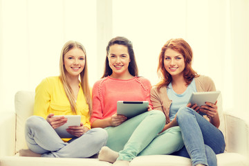 three smiling teenage girls with tablet pc at home