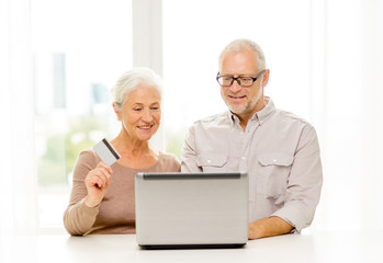 happy senior couple with laptop and credit card