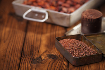 grated dark chocolate in tin with cocoa beans and solid piece in