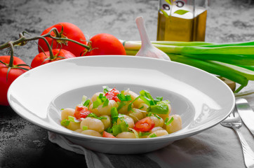 Vegetarian gnocchi with spring onions and tomatoes