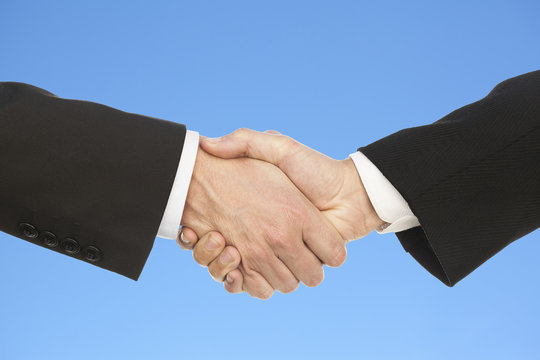 Business handshake, on beautiful blue sky background