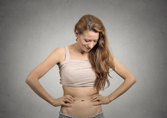 girl looks at her abdomen with concerned face expression