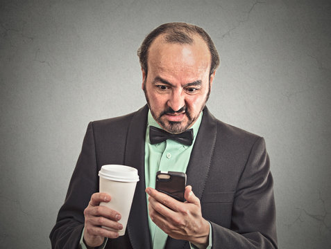 man reading bad news on smartphone drinking coffee