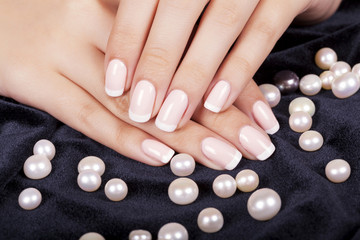 Beautiful woman's nails with french manicure and pearls.