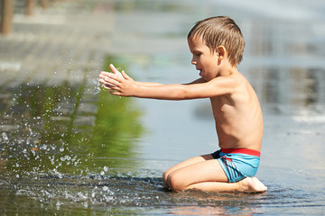 Little boy playing with water in a puddle