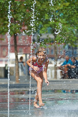 Happy girl playing in a fountain