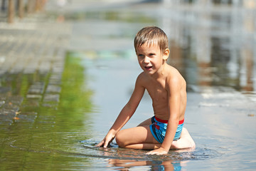 Fototapeta premium Little boy playing with water in a puddle