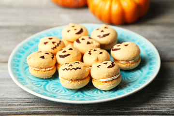 Tasty Halloween macaroons on plate, on wooden table