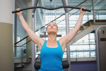 Fit brunette using weights machine for arms