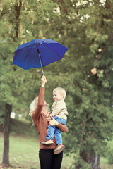 Fototapeta premium Mother and baby with umbrella walking in autumn day, soft vintag