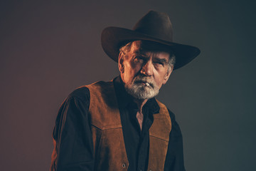 Cigarette smoking old rough western cowboy with gray beard and b