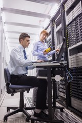 Naklejka na ściany i meble Team of technicians using digital cable analyser on servers