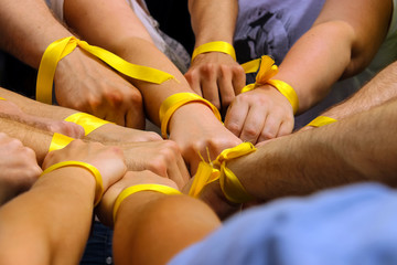 Hands with yellow ribbons together. The concept of the unity of