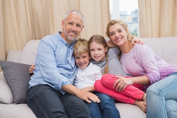 Obraz premium Happy parents with their children on sofa