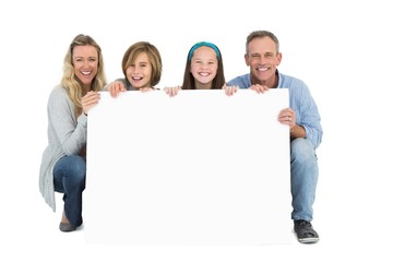 Cute family smiling at camera holding poster