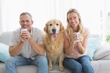 Smiling casual couple sitting on couch having coffee