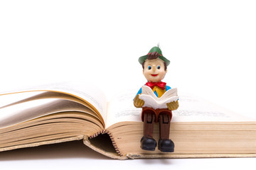 Pinocchio sitting on book isolated on white background
