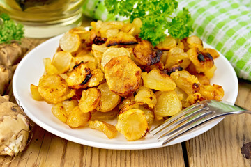 Jerusalem artichokes fried with parsley in bowl on board