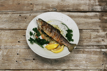 Baked fish on a white plate & vintage wooden desk