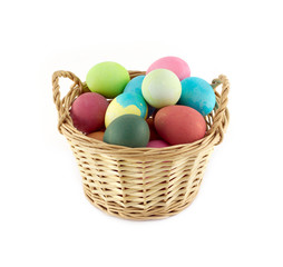 Color Easter eggs in brown basket front view isolated