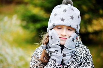 Kid girl has fun in garden with first snow