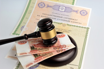 Hammer of judge with money, maternal and birth certificates on g
