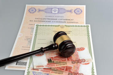 Hammer of judge with money, maternal and birth certificates on g